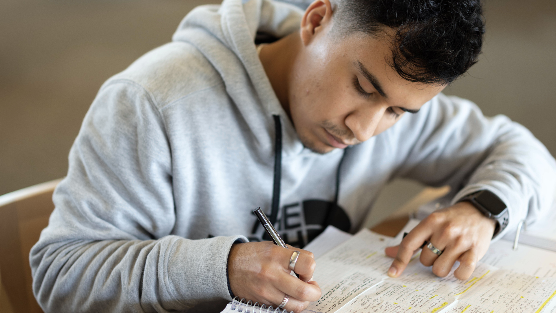 Male-presenting student taking notes in a notebook