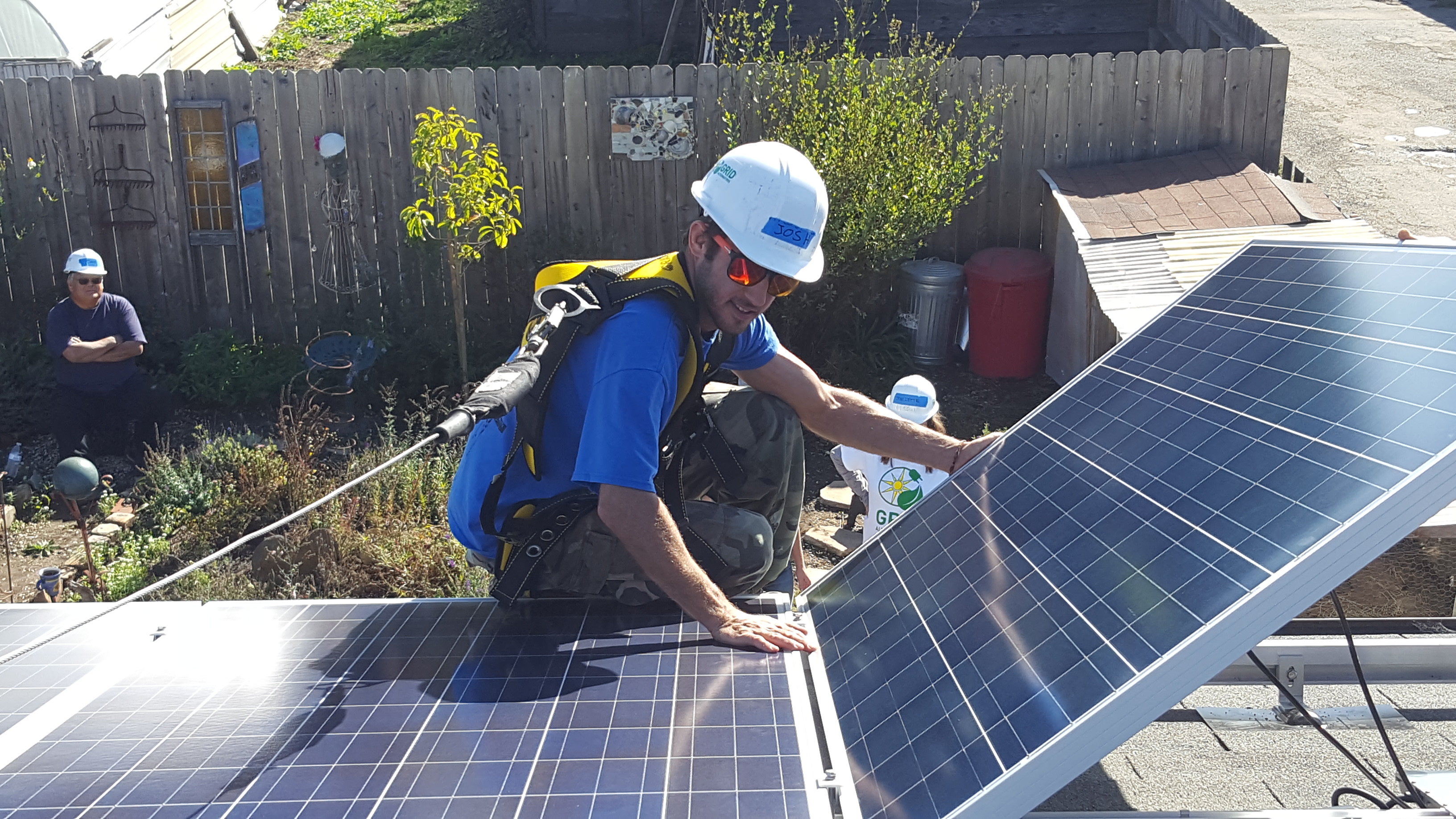 student in hard hat lifts a solar panel