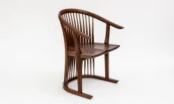 Three quarter view of a walnut Tricot Chair by artist Matt Essex, 2023, with curved legs and arms